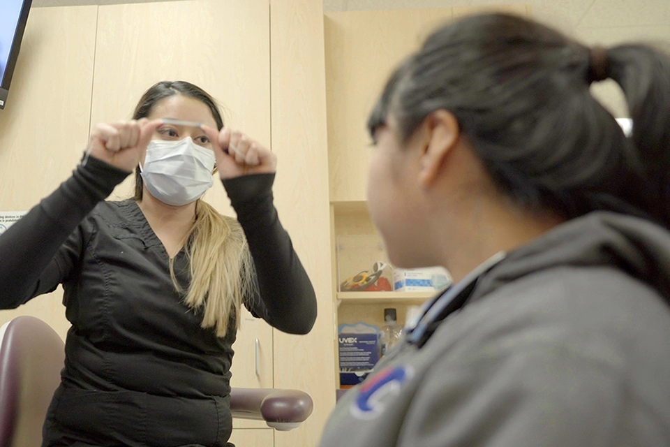 Dental hygienist doing teeth cleaning on young boy.