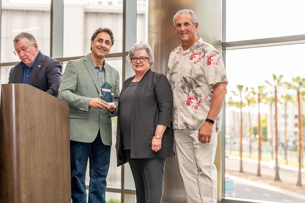 Doctor Dhar accepting award with Dr. Largent and Kevin Thomas.