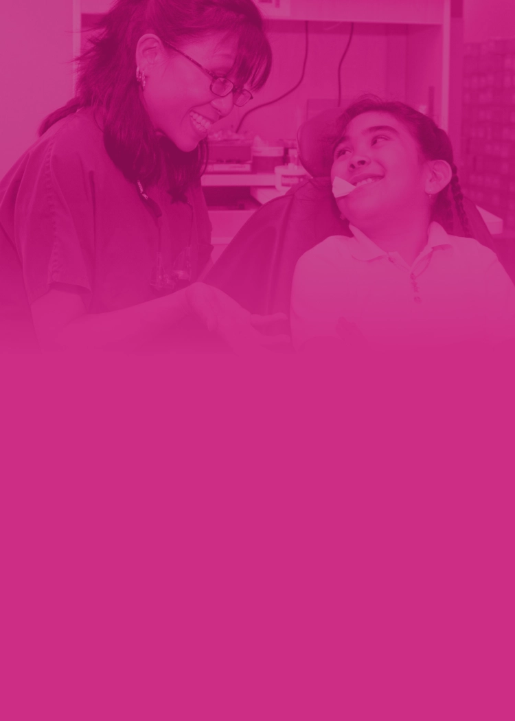 Young child in a dentist chair and a dentist both smiling.