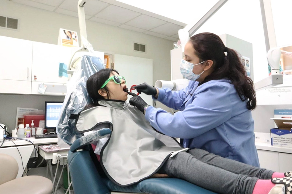 A dentist performing teeth cleaning on young girl.