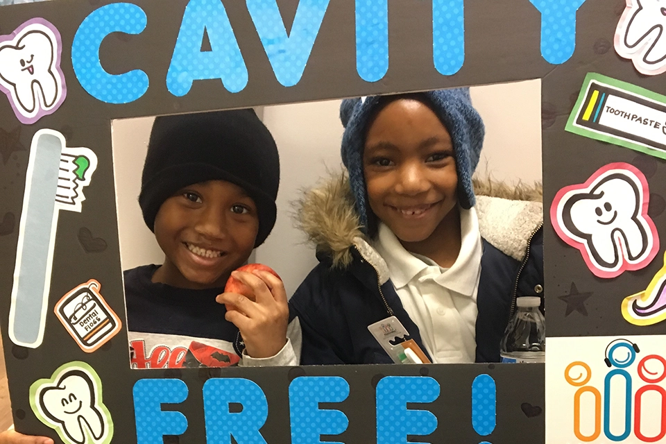 Two kids smiling and holding a cavity free sign.