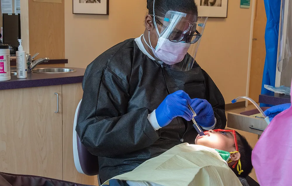 A dental hygienist doing teeth cleaning on young boy.